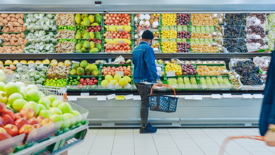 Guy with Shopping Basket Shopping for Organic Fruits and Vegetables in the Fresh Produce Section of the Store