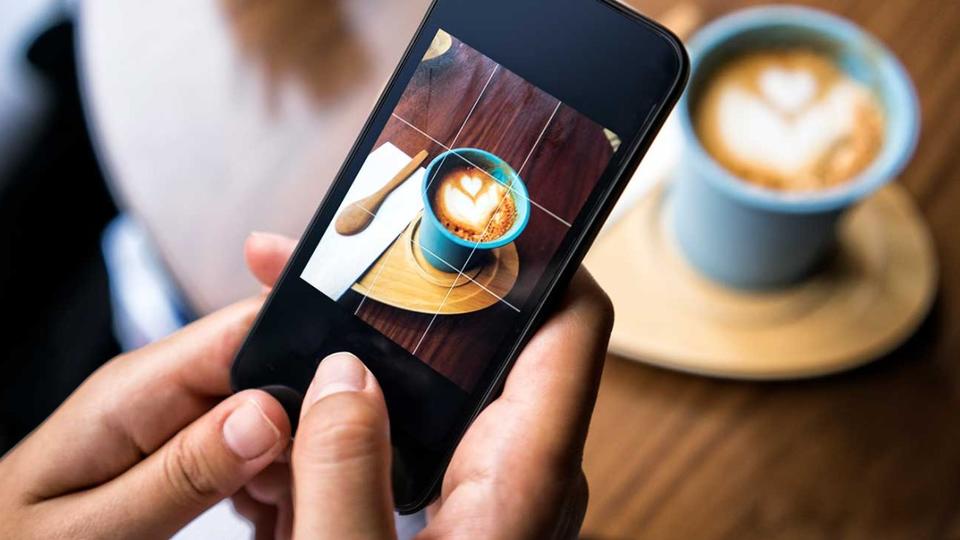 Person taking a picture of a cup of coffee with their phone